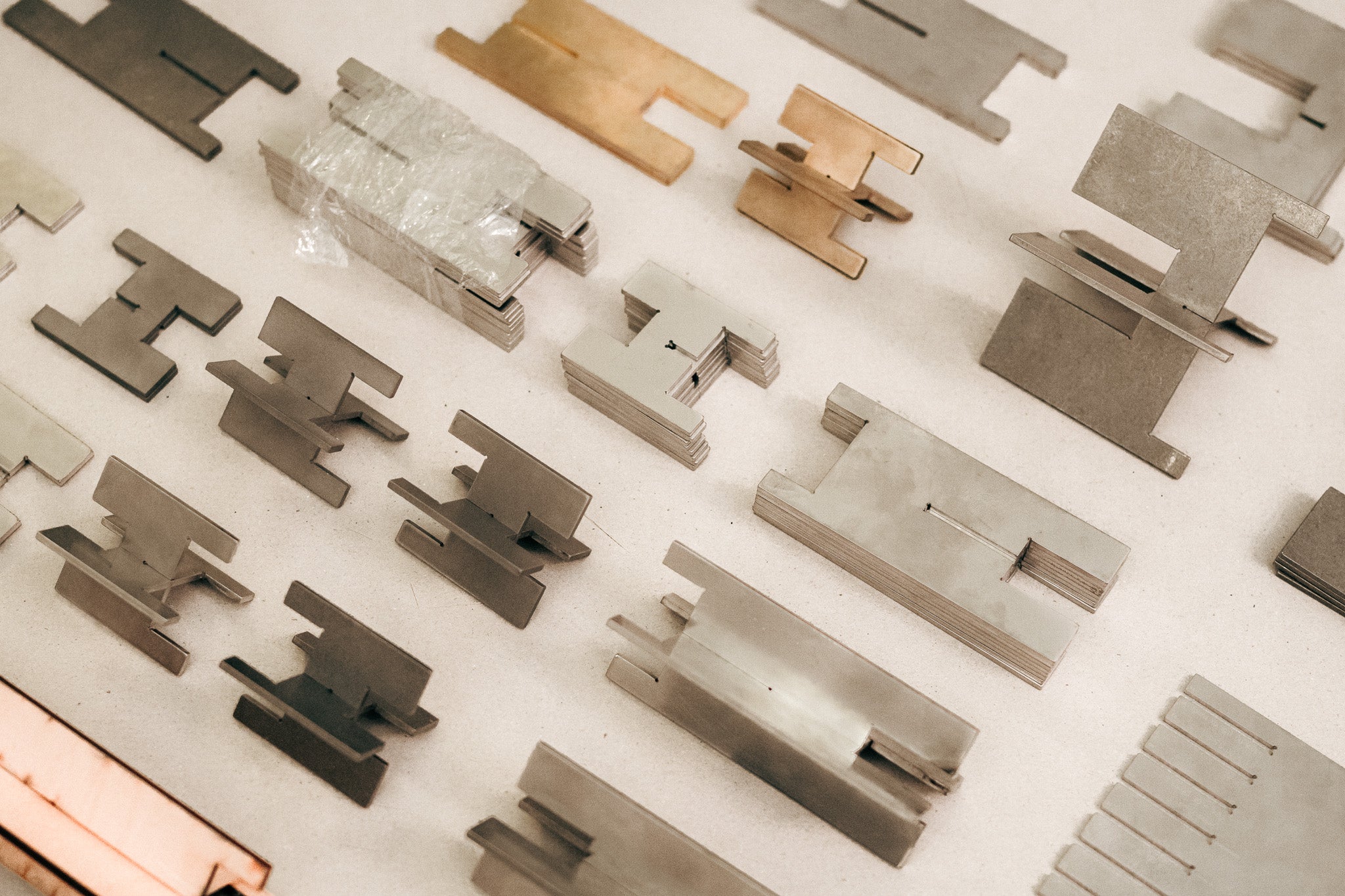 Lyssier candleholder prototypes from different metals laying flat on a neutral ground in a sorted way.